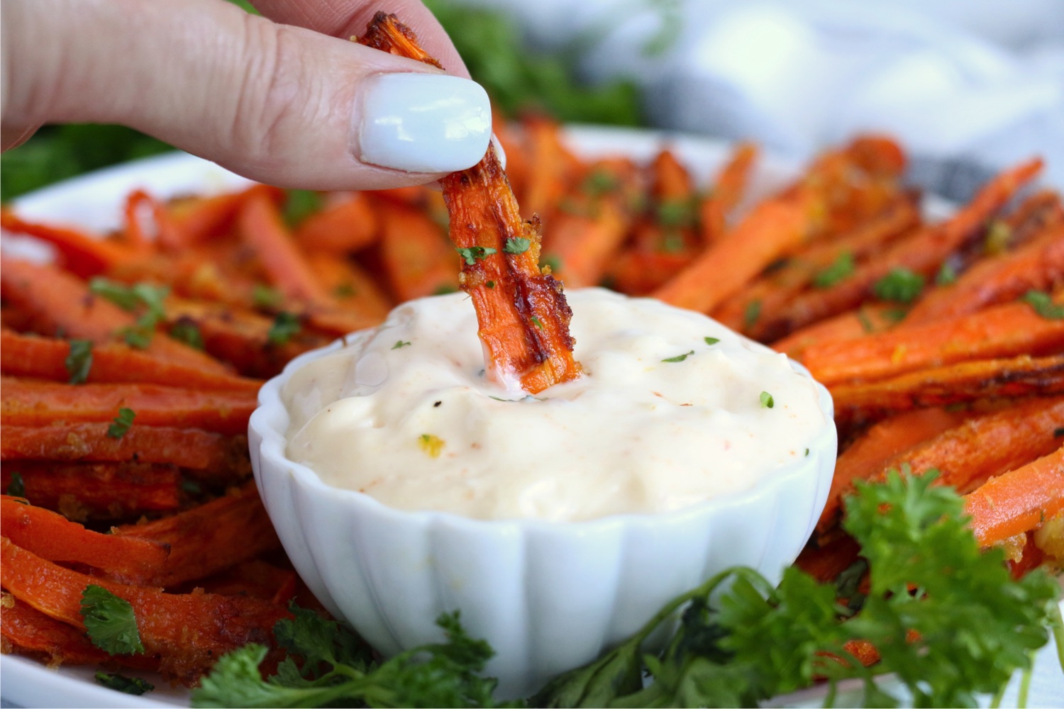 dipping an air fried carrot into spicy mayo sauce