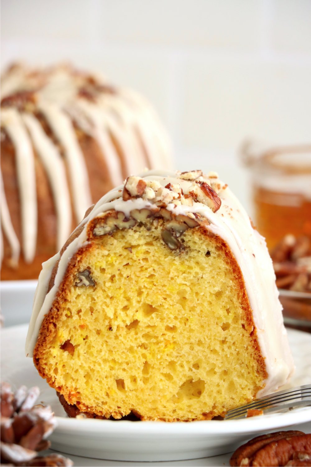 piece of rum cake in front of decorated rum cake in background