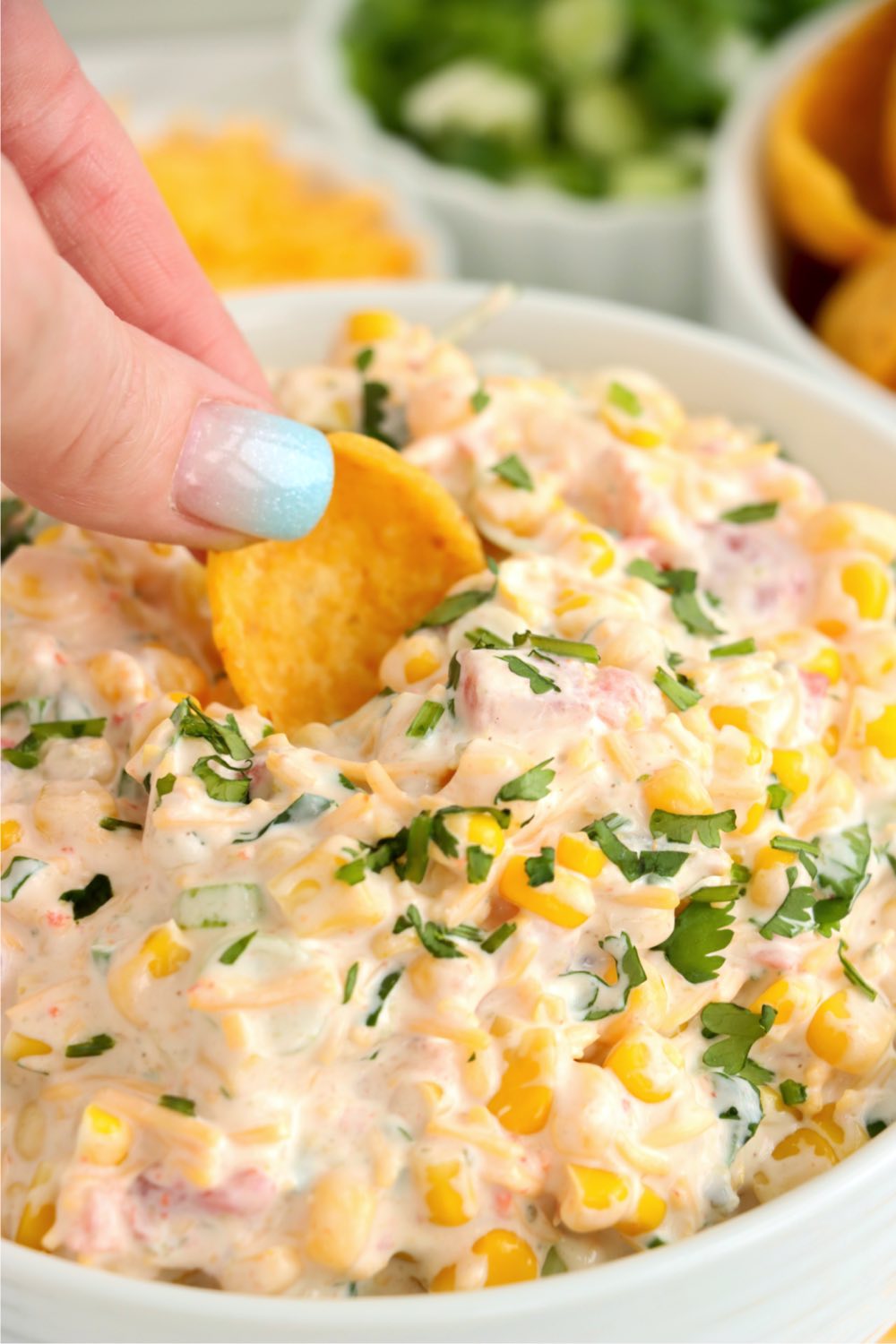 Dipping a Fritos scoop into Mexican corn dip