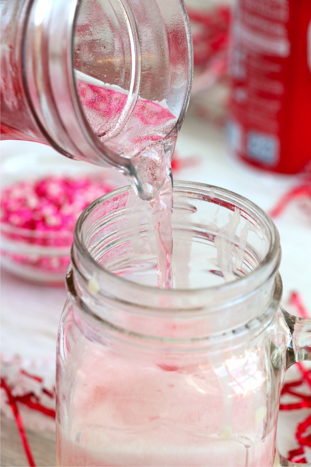 pouring cherry soda onto ice cream in a mason jar